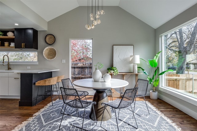 dining room with sink, dark hardwood / wood-style flooring, and vaulted ceiling