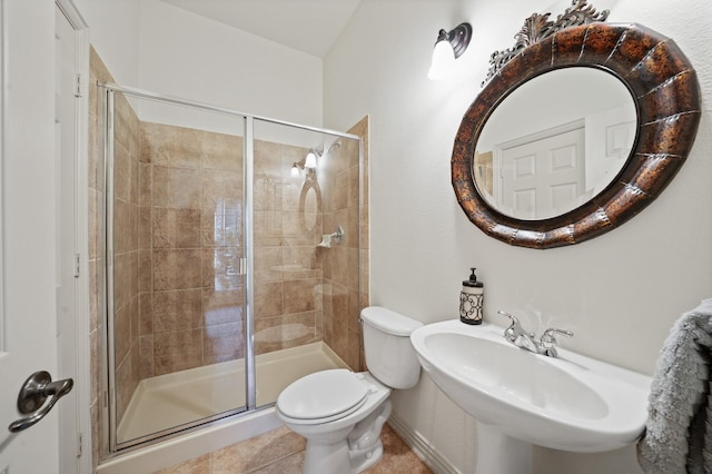 bathroom with tile patterned floors, toilet, a shower with door, and sink