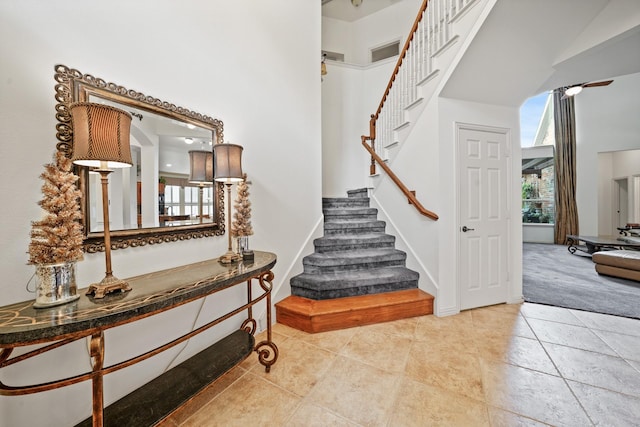 staircase with carpet floors and a towering ceiling