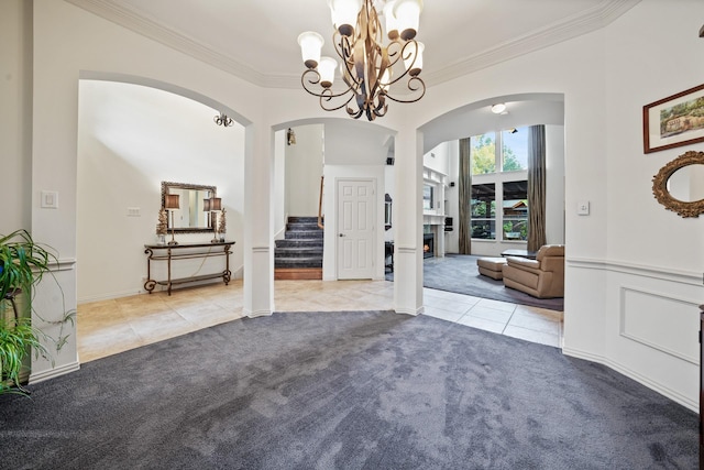 carpeted foyer entrance featuring a chandelier and crown molding