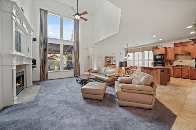 tiled living room with a high end fireplace, a high ceiling, and ceiling fan