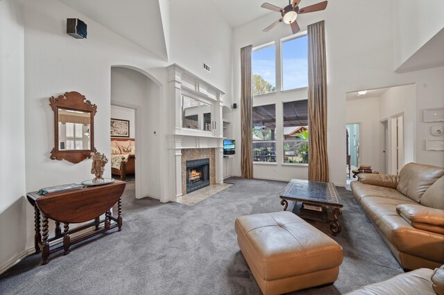 living room with a tile fireplace, light carpet, high vaulted ceiling, and ceiling fan