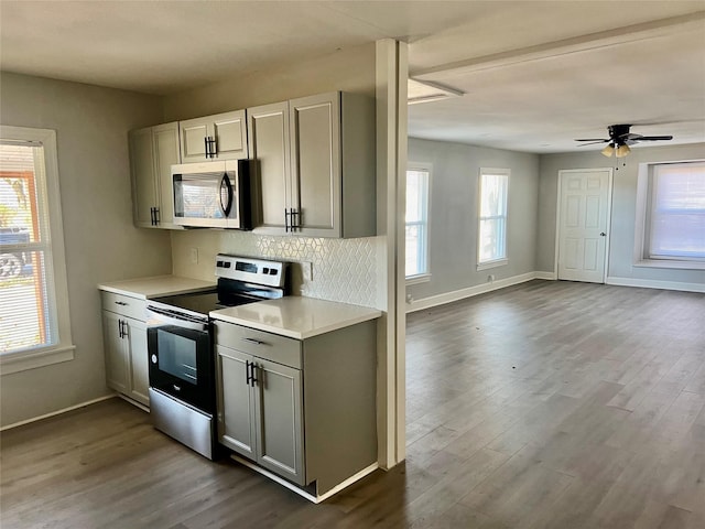 kitchen with appliances with stainless steel finishes, dark hardwood / wood-style floors, ceiling fan, and a healthy amount of sunlight