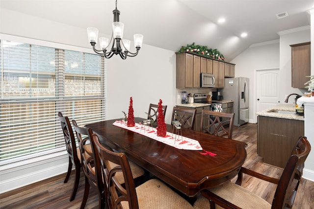 dining area featuring ornamental molding, vaulted ceiling, sink, a chandelier, and dark hardwood / wood-style floors