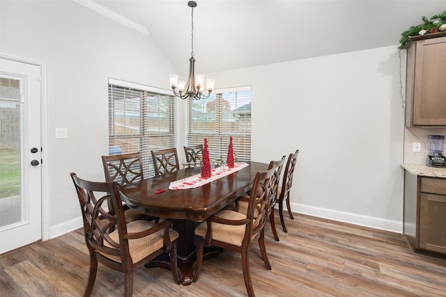 dining area featuring hardwood / wood-style flooring, vaulted ceiling, and a notable chandelier