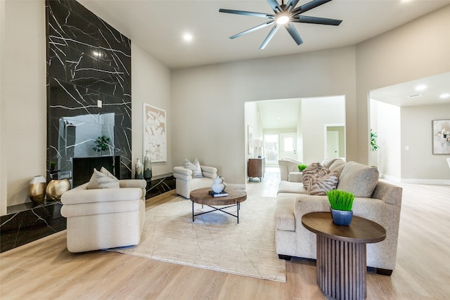 living room featuring ceiling fan, light hardwood / wood-style flooring, and a premium fireplace