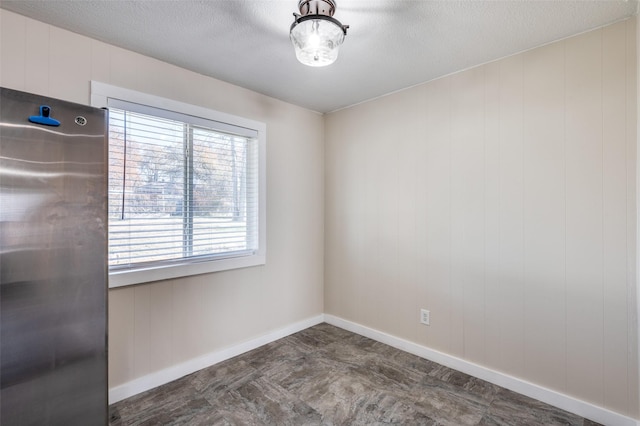 unfurnished room with wood walls and a textured ceiling