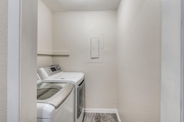 clothes washing area with washer and clothes dryer, hardwood / wood-style flooring, and electric panel