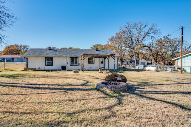 ranch-style home featuring a fire pit, central AC, and a front lawn