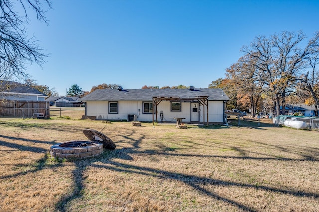 back of house with a pergola, a yard, and a fire pit