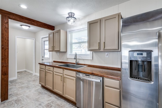 kitchen with wood counters, appliances with stainless steel finishes, a textured ceiling, and sink