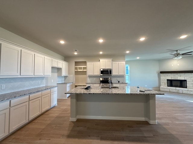 kitchen featuring white cabinetry, light stone countertops, and a kitchen island with sink