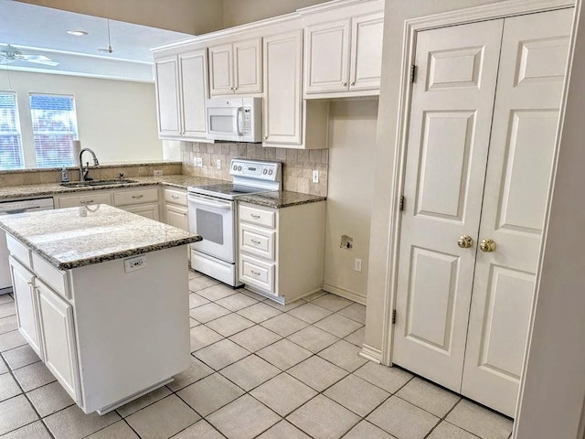 kitchen with sink, light tile patterned floors, tasteful backsplash, white appliances, and white cabinets