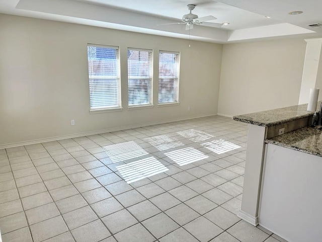 interior space with ceiling fan, light tile patterned floors, and a tray ceiling