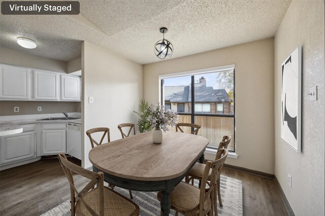 dining space featuring wood-type flooring, a textured ceiling, and sink