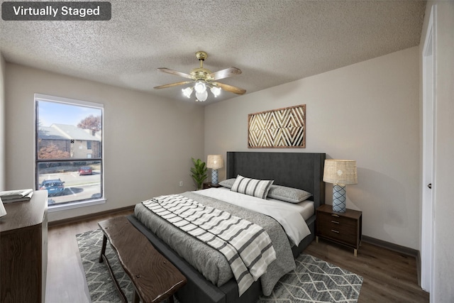 bedroom with ceiling fan, dark hardwood / wood-style flooring, a textured ceiling, and multiple windows