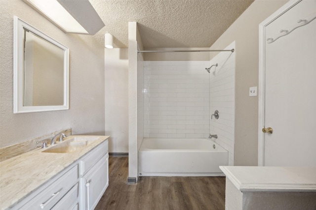 bathroom featuring hardwood / wood-style floors, vanity, a textured ceiling, and tiled shower / bath