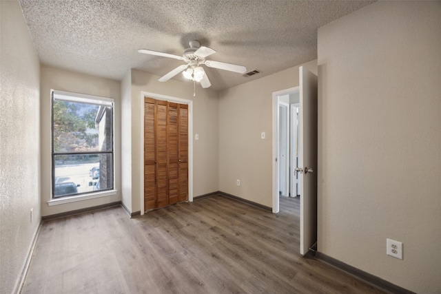 unfurnished bedroom with a closet, a textured ceiling, hardwood / wood-style flooring, and ceiling fan