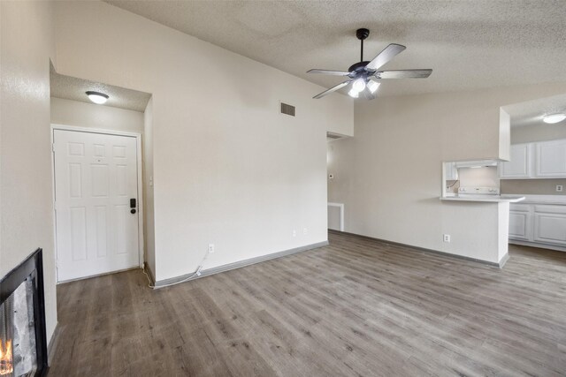 unfurnished living room featuring ceiling fan, a textured ceiling, and light wood-type flooring