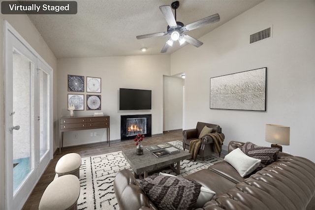 living room with a textured ceiling, ceiling fan, dark hardwood / wood-style floors, and vaulted ceiling