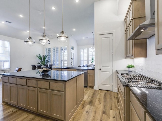 kitchen featuring pendant lighting, sink, stainless steel appliances, light wood-type flooring, and wall chimney exhaust hood