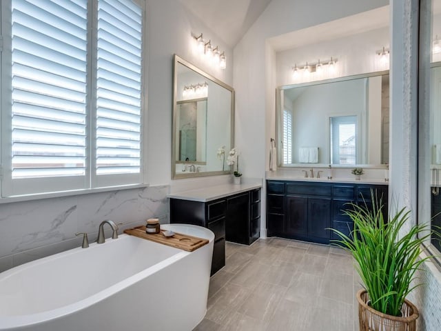 bathroom featuring vanity, lofted ceiling, and a bathtub