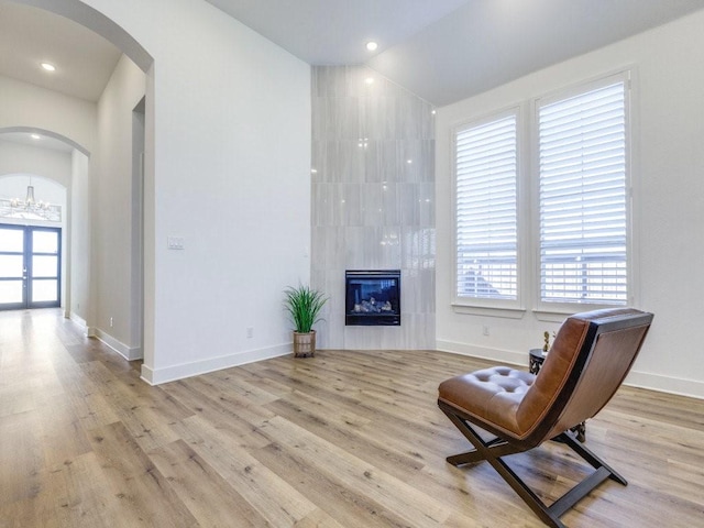 living area featuring an inviting chandelier, light hardwood / wood-style flooring, and a tile fireplace