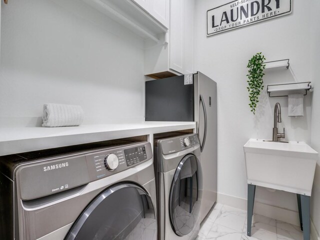 laundry room featuring separate washer and dryer and cabinets