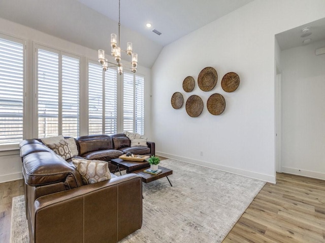 living room featuring a notable chandelier, vaulted ceiling, and light wood-type flooring