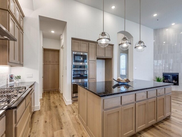 kitchen with appliances with stainless steel finishes, sink, a kitchen island, and wall chimney range hood