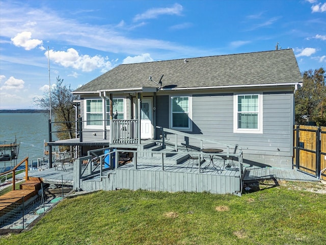 rear view of property with a deck with water view and a yard