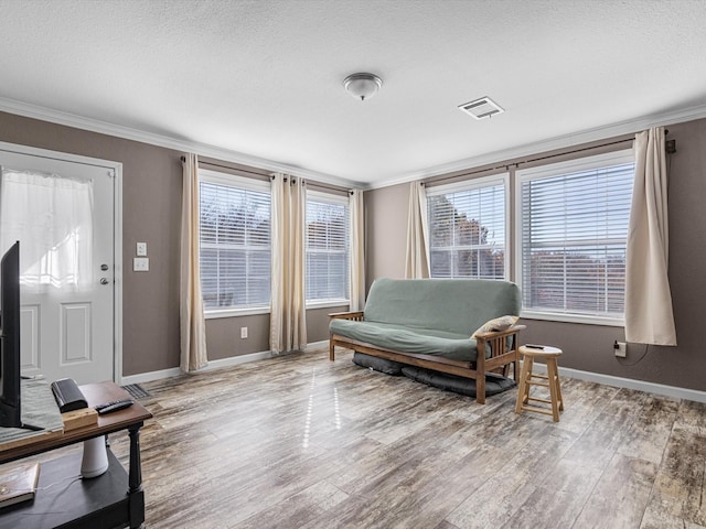 living area with crown molding, light hardwood / wood-style flooring, and a textured ceiling