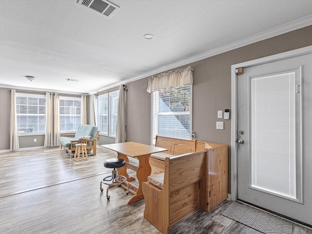 dining room with ornamental molding, hardwood / wood-style floors, and a textured ceiling