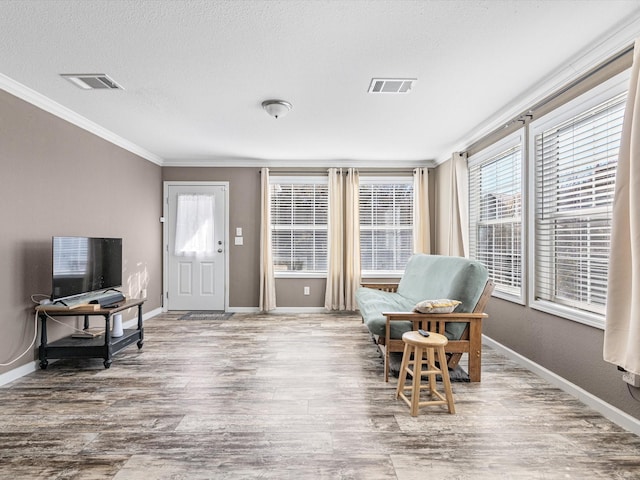 sitting room with hardwood / wood-style floors, a textured ceiling, and ornamental molding