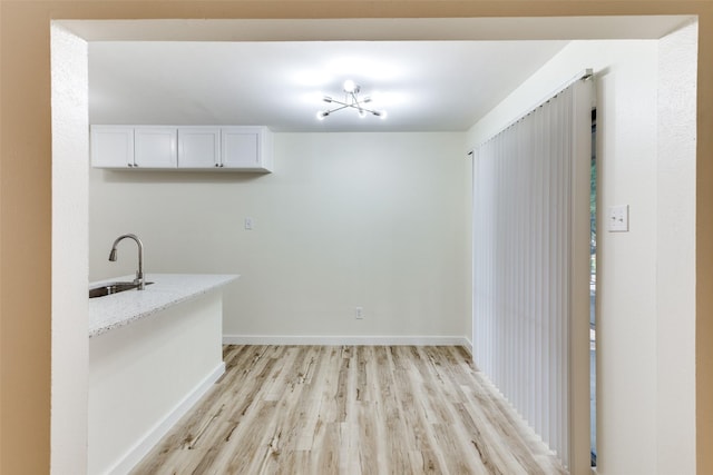 interior space featuring white cabinetry, light hardwood / wood-style floors, sink, and light stone counters