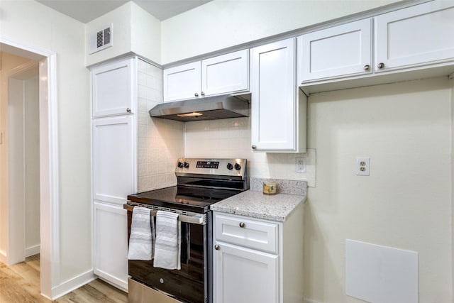 kitchen featuring stainless steel electric stove, white cabinets, decorative backsplash, light wood-type flooring, and light stone countertops