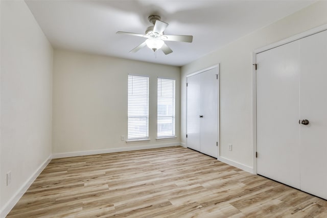 unfurnished bedroom featuring two closets, light hardwood / wood-style floors, and ceiling fan