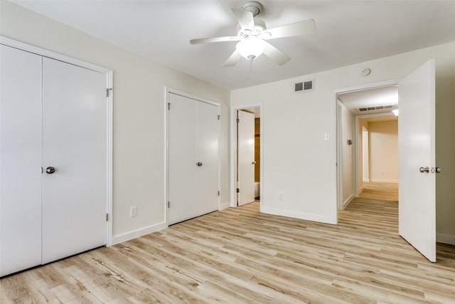 unfurnished bedroom featuring two closets, ceiling fan, and light hardwood / wood-style flooring