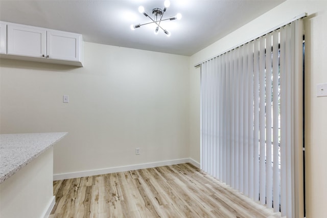 unfurnished dining area featuring a chandelier and light hardwood / wood-style flooring