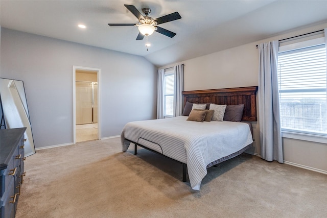 bedroom with light colored carpet, connected bathroom, vaulted ceiling, and ceiling fan