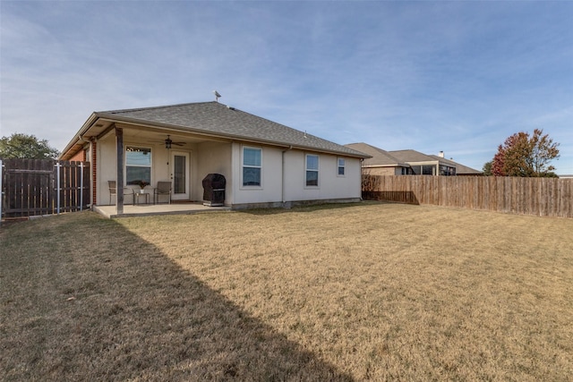 back of property featuring ceiling fan, a patio area, and a lawn