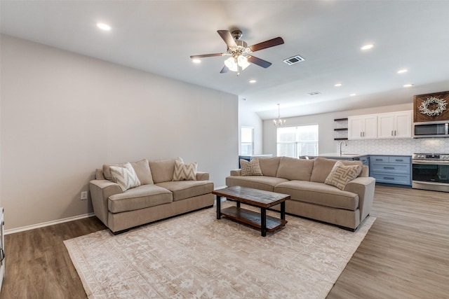 living room featuring sink, ceiling fan with notable chandelier, and light hardwood / wood-style flooring