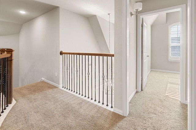 hall featuring light colored carpet and vaulted ceiling