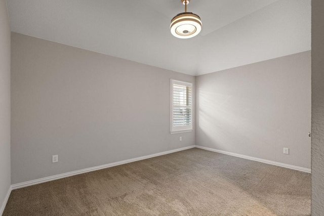 carpeted empty room featuring vaulted ceiling