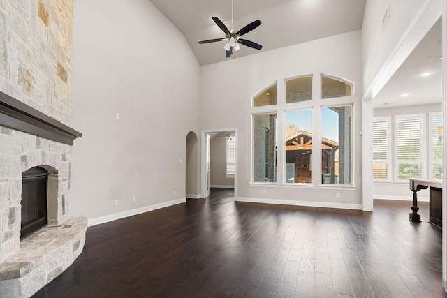 unfurnished living room featuring dark hardwood / wood-style floors, ceiling fan, a fireplace, and high vaulted ceiling