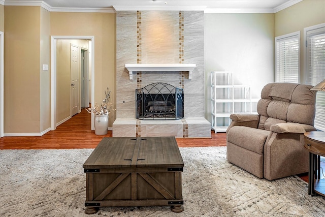 living room featuring a tiled fireplace, crown molding, and wood-type flooring