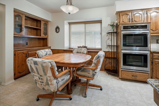 dining space with crown molding, light tile patterned floors, and wooden walls