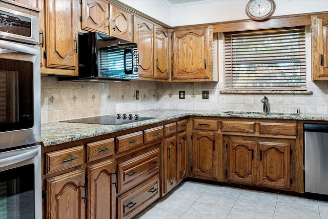 kitchen featuring light stone counters, sink, backsplash, and black appliances