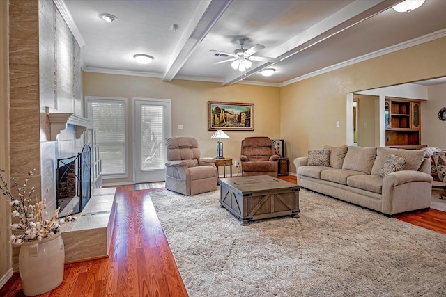 living room with beamed ceiling, ornamental molding, hardwood / wood-style flooring, ceiling fan, and a fireplace