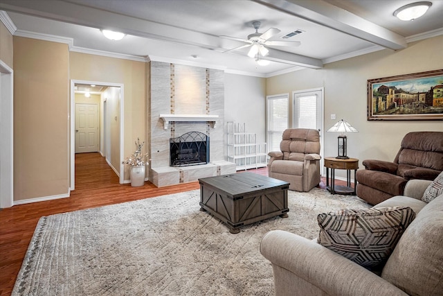 living room featuring crown molding, wood-type flooring, a large fireplace, ceiling fan, and beam ceiling